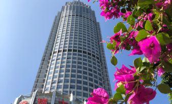 The hotel complex features a visually striking architectural composition, with a tall building reflecting another skyscraper behind it at Swissotel Foshan Guangdong