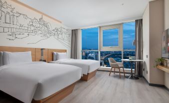 The bedroom features double beds, large windows, and a city view from one side at UrCove by HYATT Nanjing South Railway Station