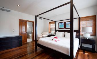 a large bedroom with a four - poster bed , hardwood floors , and a bathtub in the background at Residences at Nonsuch Bay Antigua