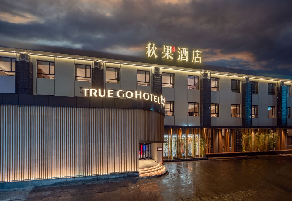 At night, the front entrance of a hotel is adorned with signs in Chinese and Japanese at Qiuguo Hotel (Beijing Sanlitun Gongti Branch)