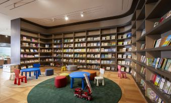 a large room filled with bookshelves and toys , including a round table with a slide at Lahan Hotel Jeonju