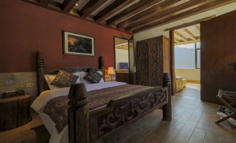 A bedroom is furnished with a large bed and a wooden table in the center, with an open door beside it at Hotel Blanche