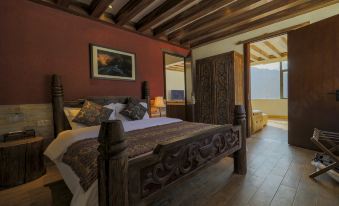 A bedroom is furnished with a large bed and a wooden table in the center, with an open door beside it at Hotel Blanche Yading