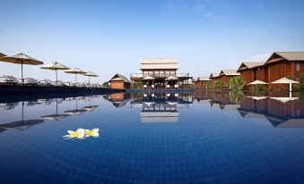 a large swimming pool surrounded by lounge chairs and umbrellas , with a building in the background at Duyong Marina & Resort