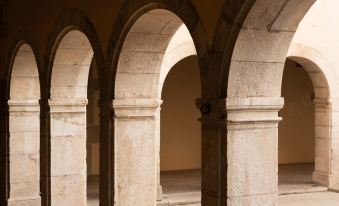 an old stone building with three arches , providing a view of the interior through the windows at L'Hotel de Beaune