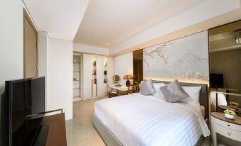 a large bed with white linens is in a room with a flat screen tv at Oakwood Apartments Pik Jakarta