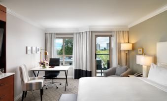 a modern hotel room with a balcony , white bed , gray sofa , desk , and other amenities at Hotel Grand Pacific