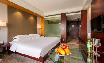 There is a large bed in the middle room of the hotel, accompanied by a table and chair at Maision New Century Hotel Keqiao Shaoxing