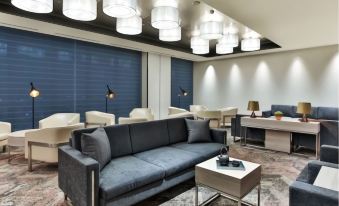 a modern lounge area with a gray couch , white table , and large hanging lights , creating a comfortable atmosphere for guests at Oakwood Suites Yokohama