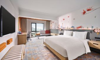 The room is furnished like an upscale space, featuring large windows, a bed, and a desk in the center at Hilton Garden Inn Guangzhou Tianhe