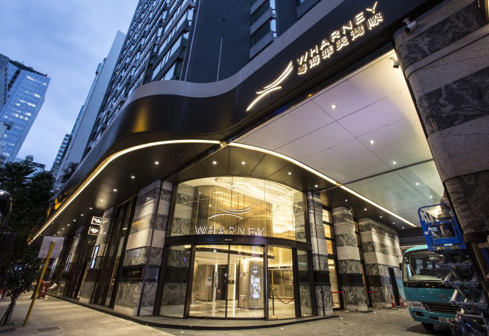 The entrance to a hotel is adorned with an illuminated sign above its glass front door at Wharney Hotel