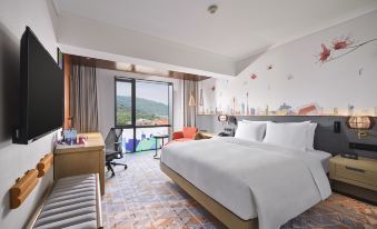 The modern bedroom features large windows, a double bed, and a desk in the middle with a view at Hilton Garden Inn Guangzhou Tianhe