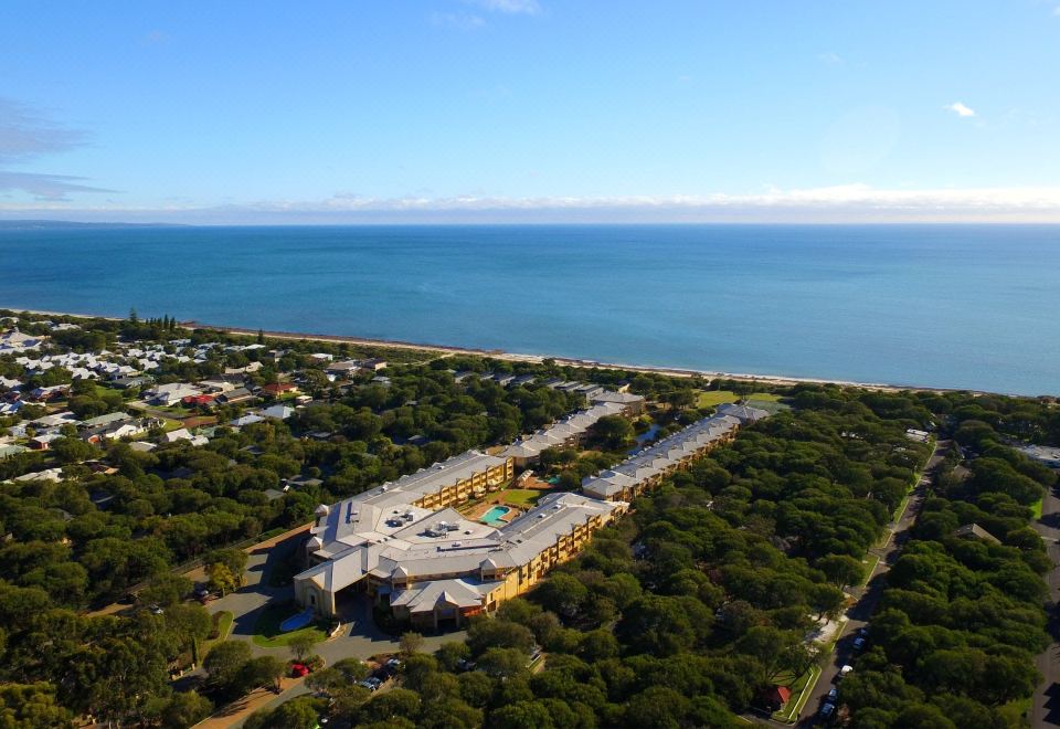 a bird 's eye view of a building with trees surrounding it and the ocean in the background at Abbey Beach Resort