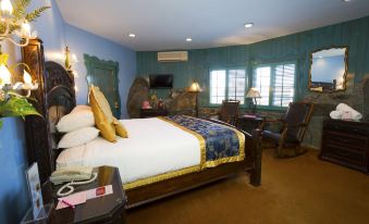 a large bed with a white comforter and gold throw pillow is in a room with blue walls at Madonna Inn