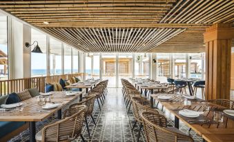 a large dining room with wooden tables and chairs arranged for a group of people at Tui Blue Nam Hoi An