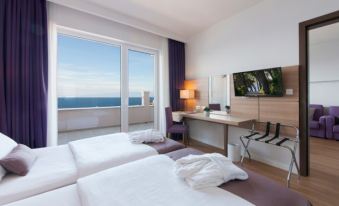 a hotel room with two beds , a desk , and a large window overlooking the ocean at Vitality Hotel Punta