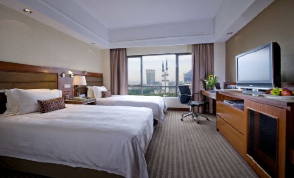 a hotel room with two beds , a desk , and a window overlooking the city , giving a sense of comfort and relaxation at Concorde Hotel Shah Alam