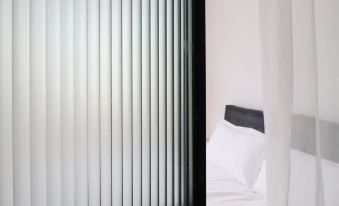 A bedroom with white walls and wood flooring, featuring a bed positioned towards an open door at CITY PARK HOTEL