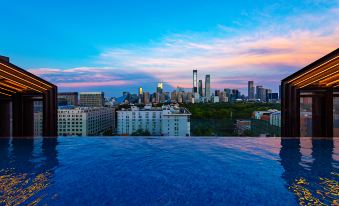 The pool offers a picturesque view at sunset, showcasing the city skyline against a backdrop of a clear blue sky at Livefortuna Hotel