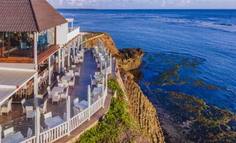a restaurant with white tables and chairs is situated on a cliff overlooking the ocean at Sea Cliff Hotel