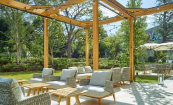 a patio area with wooden pergolas , chairs , and a dining table set up for outdoor dining at Mitsui Garden Hotel Jingugaien Tokyo Premier