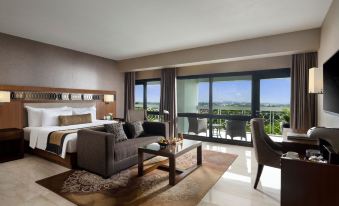 a luxurious hotel room with a large bed , couch , and balcony offering a view of the city at Royal Ambarrukmo Yogyakarta