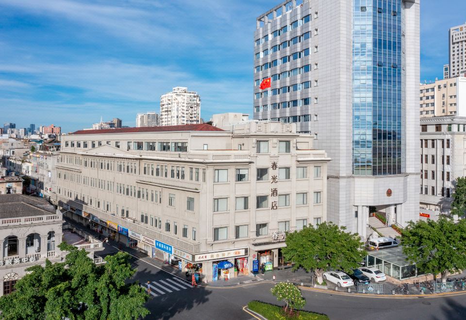 A large building with numerous windows is located at an intersection, with other buildings in front at Chunguang Hotel