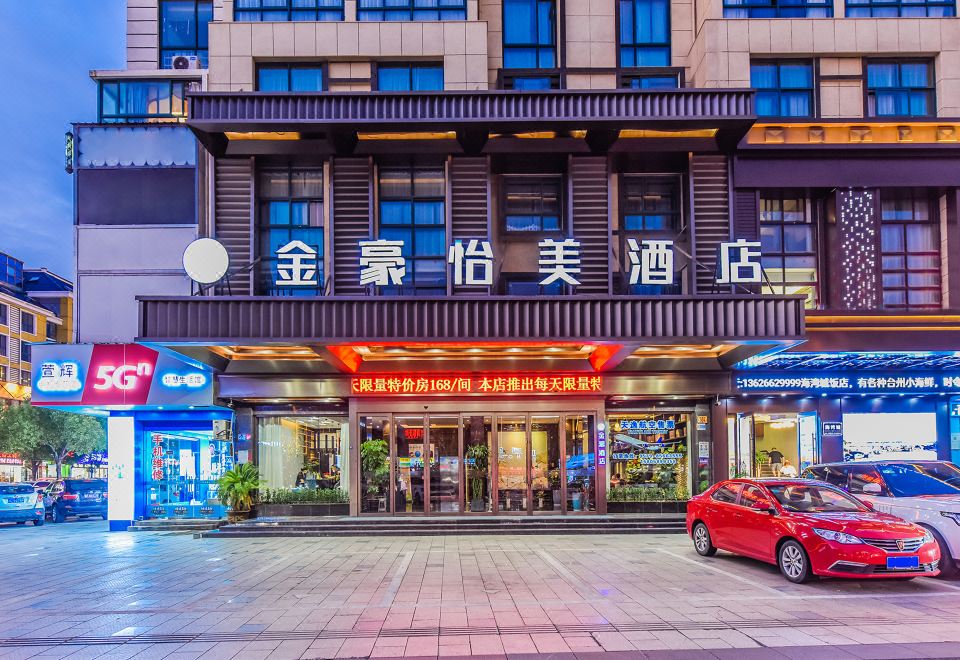 Cars pass by as guests enter the front entrance of a hotel in an oriental city at JinHao YiMei Hotel