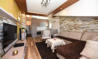 a modern living room with a brown couch , wooden floor , and stone wall behind the couch at D&D Apartments