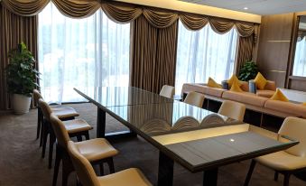 a modern dining room with a glass table , chairs , and a couch in the background at Muong Thanh Luxury Son La