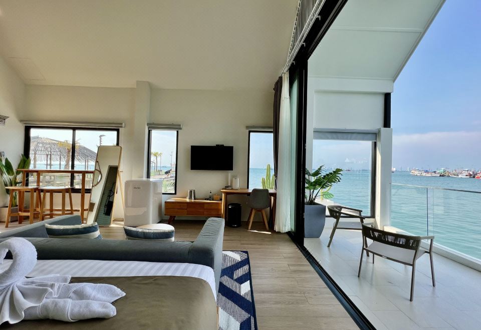 a luxurious hotel room with a large window overlooking the ocean , featuring two beds and a balcony at Baan Tah on the Sea