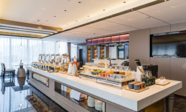 a large dining room with a long white buffet table filled with various food items and beverages at Atour Hotel