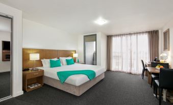 a large bed with a wooden headboard and white linens is in a room with a window at Quest Cheltenham