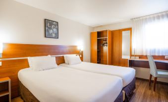 a hotel room with two beds , a nightstand between them , and a wooden headboard on the wall at Comfort Hotel Aeroport Lyon St Exupery