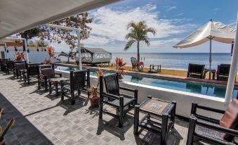 a rooftop terrace with several black chairs and umbrellas , overlooking the ocean , under a clear blue sky at The Beachhouse