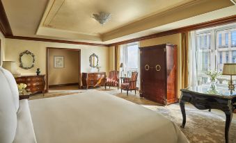 a luxurious hotel room with a large bed , wooden furniture , and a view of the city at Four Seasons Hotel Cairo at the First Residence