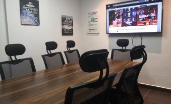 a conference room with a wooden table , black chairs , and a large screen on the wall at Monaco Hotel