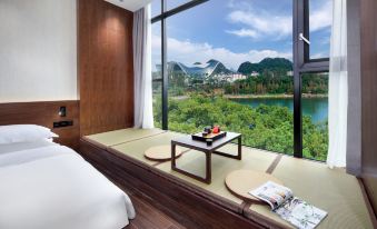 The bedroom features large windows that offer views of the water and mountains, and it includes an elevated bed at WING HOTEL