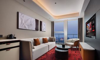 A living room with large windows and a balcony that overlooks the city at one end at Radisson RED Guang Zhou South Railway Station