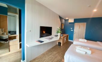 a hotel room with two beds , a tv on the wall , and a desk in the corner at Hotel Fuse Rayong