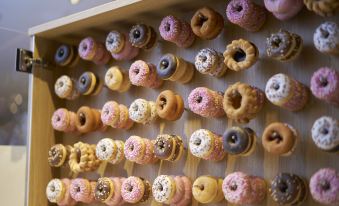 a display of various donuts in different colors and flavors , arranged on wooden sticks , against a white background at Oriental Hotel Tokyo Bay
