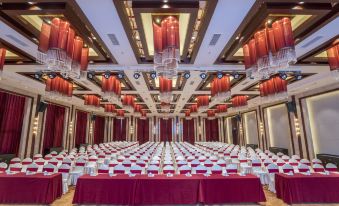 a large , empty conference room with red and white tablecloths , set up for a formal event at Orient Hotel