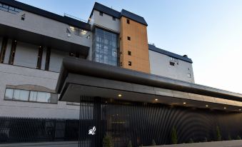 a modern building with a large glass window and a black entrance , under a clear blue sky at The Lake View Toya Nonokaze Resort