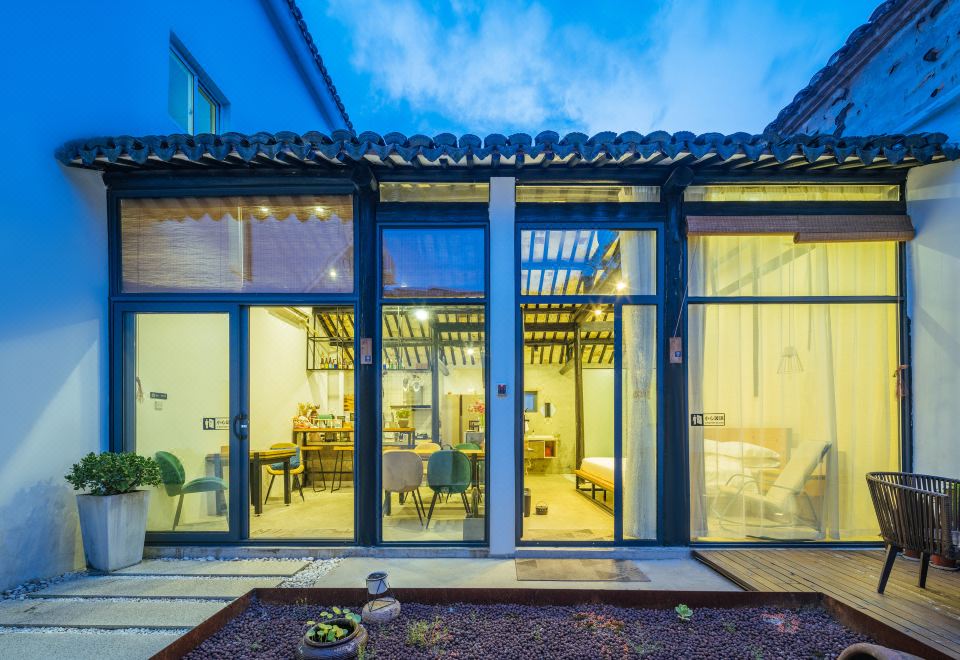 a modern house with large glass doors that open up to a dining area and a kitchen at Floral Hotel · Mowan hotel (Tongli Ancient Town)