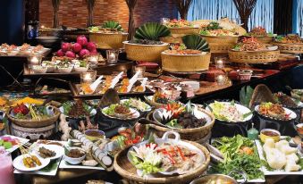 a large dining table filled with a variety of dishes , including meat , vegetables , and other food items at Hotel Maya Kuala Lumpur City Centre