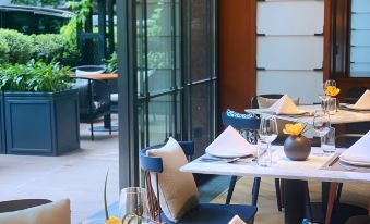 The restaurant has tables and chairs, with a window providing a view of another room at Hilton Garden Inn Guangzhou Tianhe