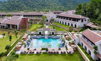 aerial view of a resort with a large pool surrounded by buildings , umbrellas , and lounge chairs at Legacy Yen Tu - MGallery