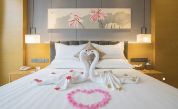 a hotel room with a king - sized bed adorned with rose petals and a swan made of towels at Orient Hotel