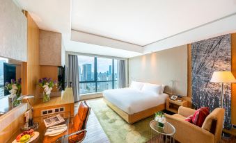 A bedroom with large windows, a bed, and a desk in the center faces outward at The Eton Hotel Shanghai