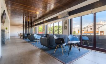 a modern lounge area with blue chairs and a large window , providing natural light and views of the outdoors at AquaHotel